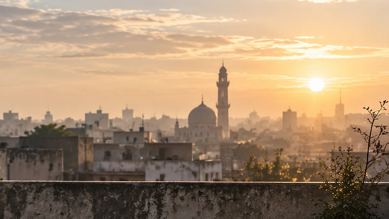 The sun rising over a hazy skyline and a minaret